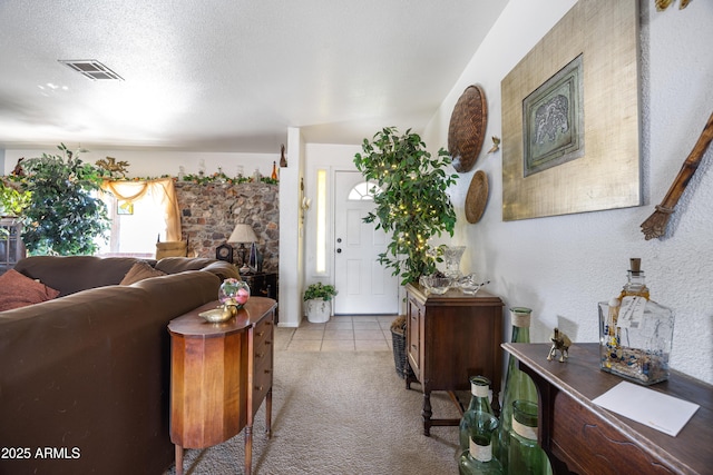 living room featuring light carpet, light tile patterned floors, visible vents, and a textured ceiling