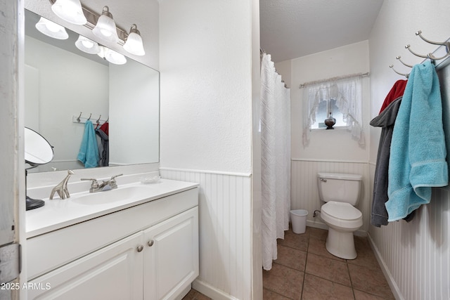 full bathroom featuring a wainscoted wall, vanity, toilet, and tile patterned floors