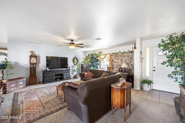 living area featuring a textured ceiling, ceiling fan, light tile patterned floors, and visible vents