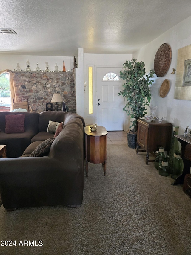 living area with tile patterned flooring, carpet, visible vents, and a textured ceiling