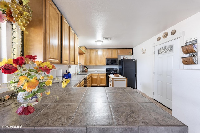 kitchen with visible vents, a sink, a peninsula, and black appliances