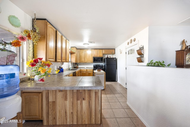 kitchen featuring light tile patterned floors, visible vents, freestanding refrigerator, a peninsula, and a sink