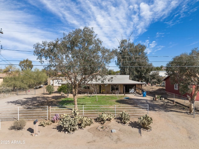 view of front of home featuring dirt driveway, fence, and a carport