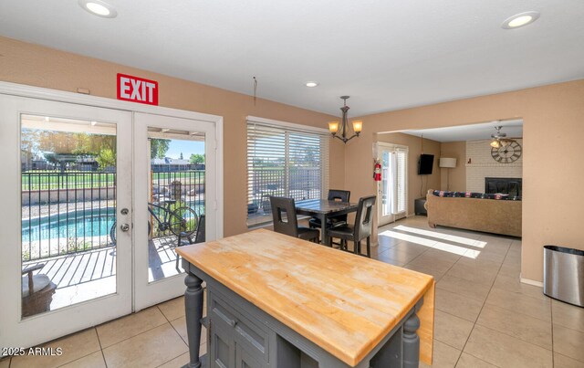 dining area with a fireplace, recessed lighting, french doors, light tile patterned floors, and a notable chandelier