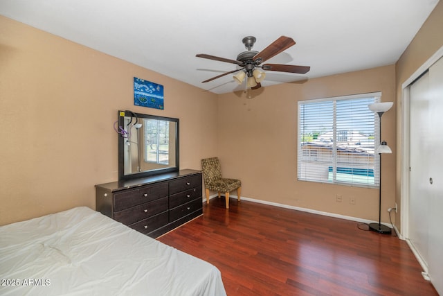 bedroom featuring baseboards, a ceiling fan, dark wood-style flooring, and a closet