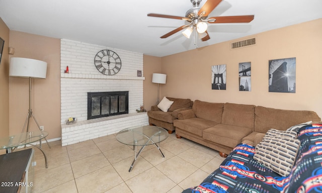 tiled living area featuring a brick fireplace, ceiling fan, and visible vents