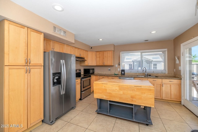 kitchen featuring light brown cabinetry, appliances with stainless steel finishes, a sink, butcher block countertops, and under cabinet range hood