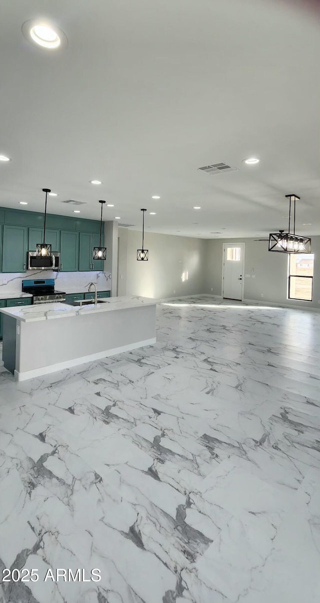 interior space featuring appliances with stainless steel finishes, decorative light fixtures, light stone countertops, and sink