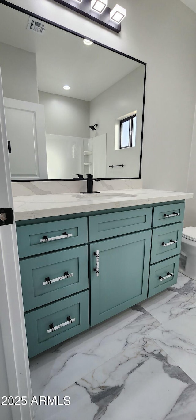 bathroom with vanity, toilet, and a shower