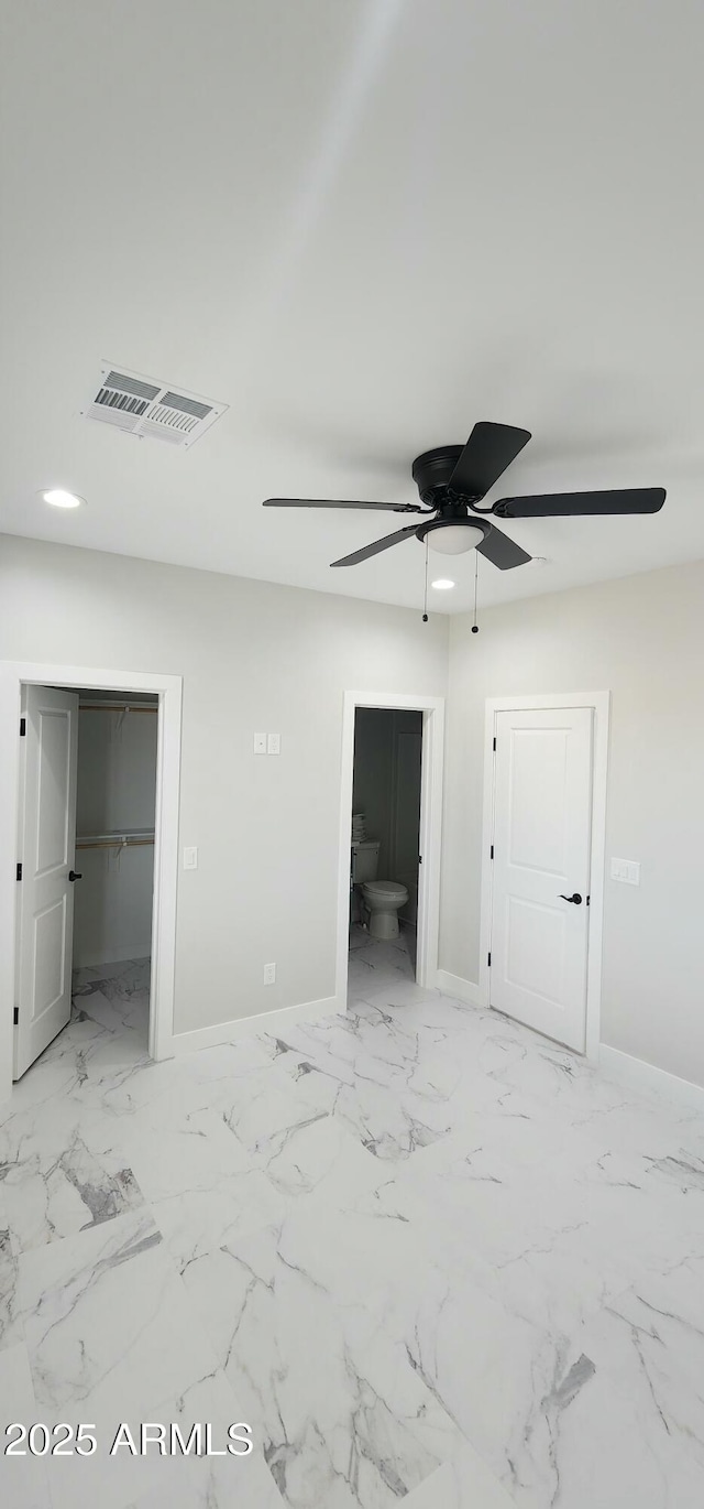 unfurnished bedroom with a walk in closet, a closet, ceiling fan, and ensuite bathroom