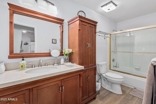 full bathroom featuring vanity, hardwood / wood-style floors, toilet, and combined bath / shower with glass door