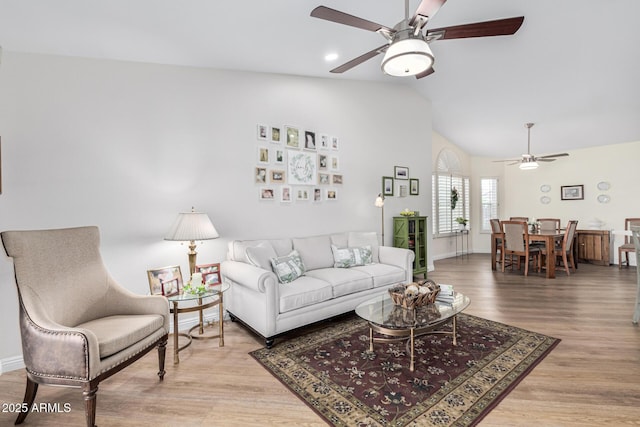 living room with lofted ceiling, light hardwood / wood-style flooring, and ceiling fan