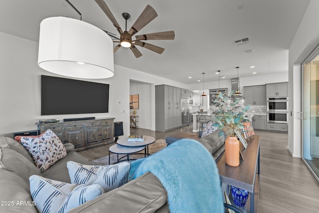 living room with ceiling fan and light hardwood / wood-style floors