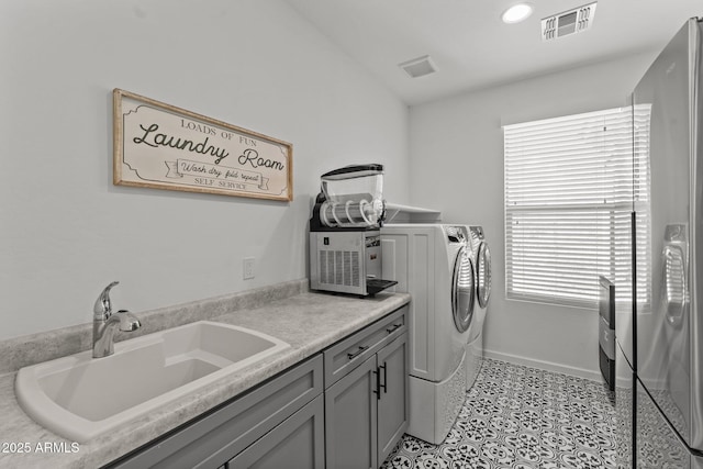 clothes washing area featuring cabinets, washing machine and clothes dryer, sink, and a wealth of natural light