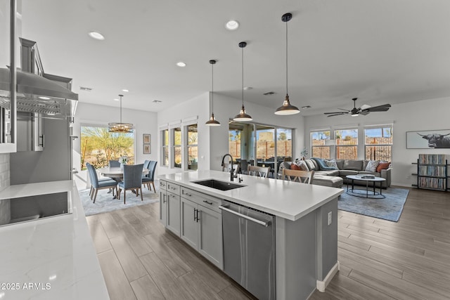 kitchen with pendant lighting, a kitchen island with sink, dishwasher, and sink