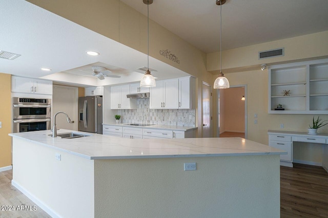 kitchen with stainless steel appliances, white cabinets, light stone counters, and hanging light fixtures