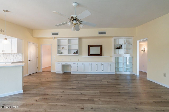 unfurnished living room with built in shelves, hardwood / wood-style floors, and ceiling fan