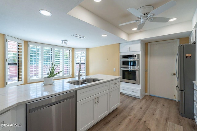 kitchen featuring light wood-type flooring, sink, white cabinetry, stainless steel appliances, and ceiling fan