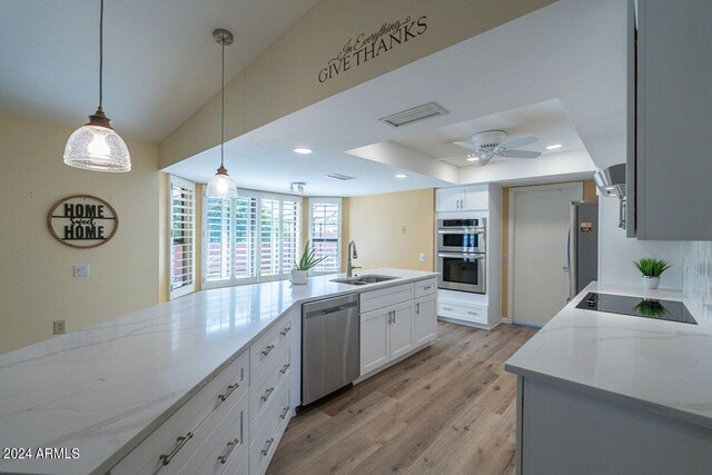 kitchen with sink, light hardwood / wood-style flooring, white cabinetry, appliances with stainless steel finishes, and light stone countertops