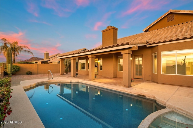 pool at dusk with a patio area