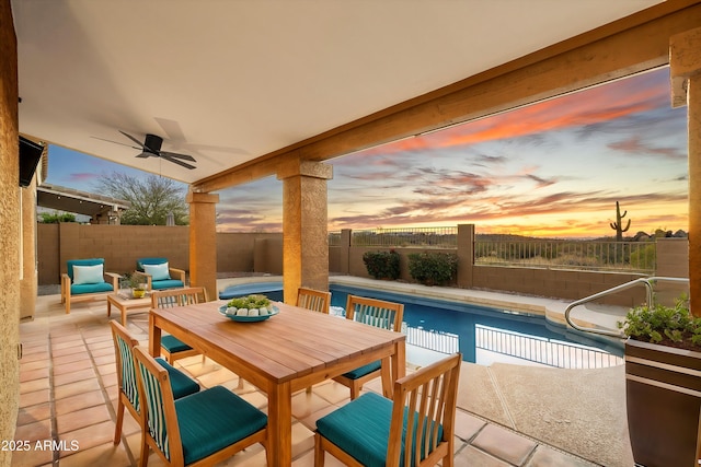 patio terrace at dusk with a fenced in pool and ceiling fan