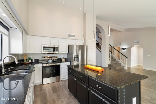 kitchen featuring a kitchen island, appliances with stainless steel finishes, white cabinetry, sink, and dark stone countertops