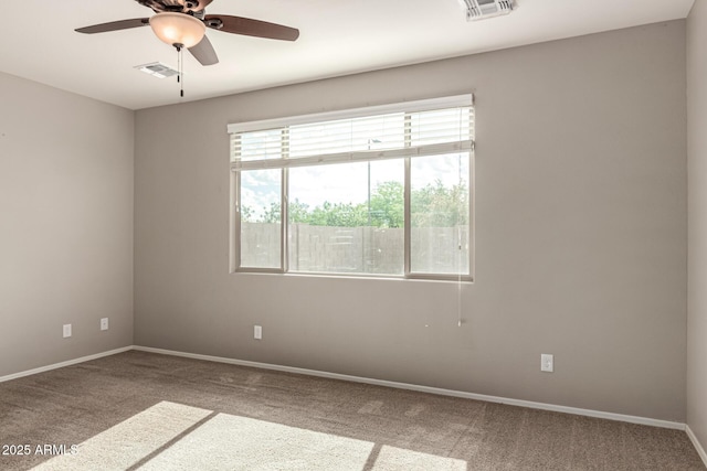 empty room with carpet floors, ceiling fan, baseboards, and visible vents