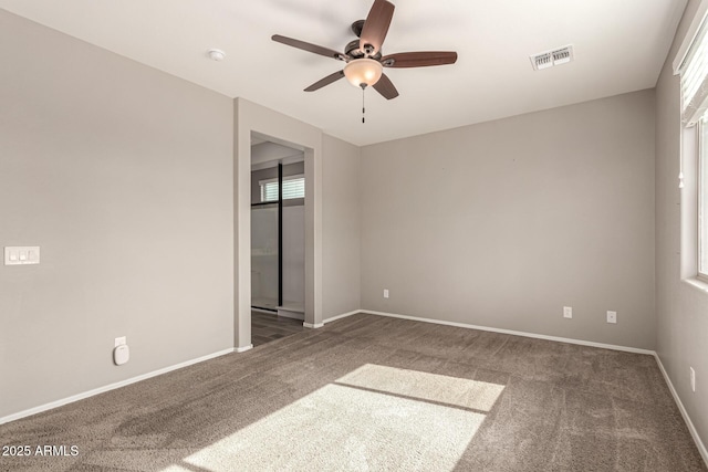 carpeted spare room featuring baseboards, ceiling fan, and visible vents