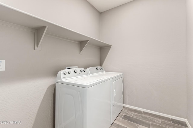 clothes washing area featuring separate washer and dryer, laundry area, baseboards, and wood tiled floor
