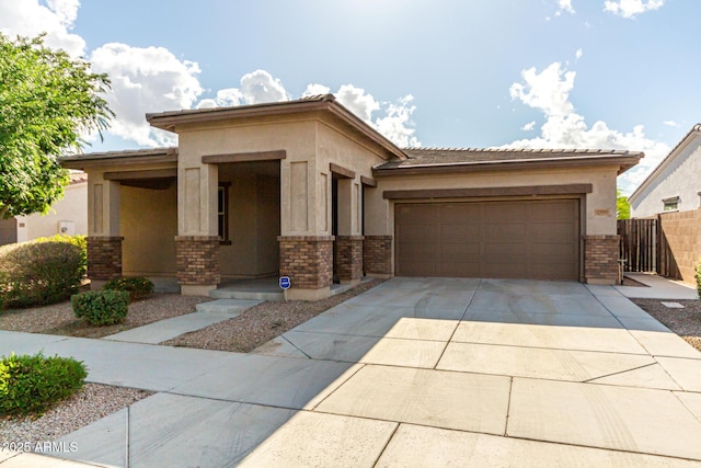 prairie-style home with an attached garage, stucco siding, brick siding, and concrete driveway