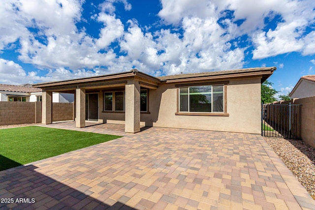 rear view of property with a fenced backyard, a patio, and stucco siding