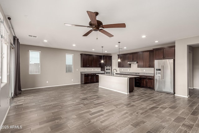 kitchen with visible vents, dark brown cabinetry, open floor plan, light countertops, and stainless steel appliances