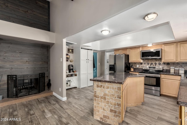 kitchen with a center island, stainless steel appliances, light brown cabinets, and light hardwood / wood-style flooring