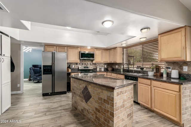 kitchen with light brown cabinetry, tasteful backsplash, stainless steel appliances, light hardwood / wood-style flooring, and a kitchen island