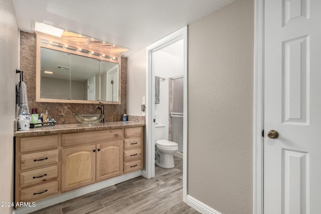 bathroom featuring toilet, vanity, a shower with door, and hardwood / wood-style flooring