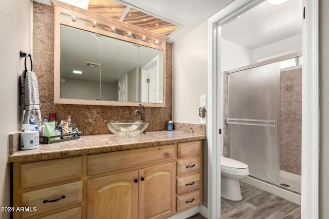 bathroom with vanity, toilet, wood-type flooring, and a shower with door