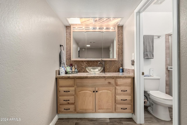 bathroom with hardwood / wood-style floors, vanity, toilet, and a skylight