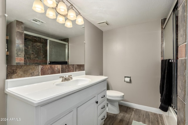 bathroom featuring vanity, hardwood / wood-style flooring, toilet, a shower with shower door, and a chandelier