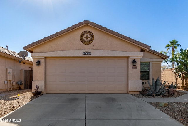 ranch-style house featuring a garage, a tiled roof, concrete driveway, and stucco siding