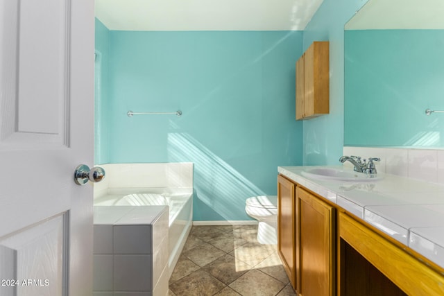 bathroom with tile patterned flooring, vanity, toilet, and tiled tub