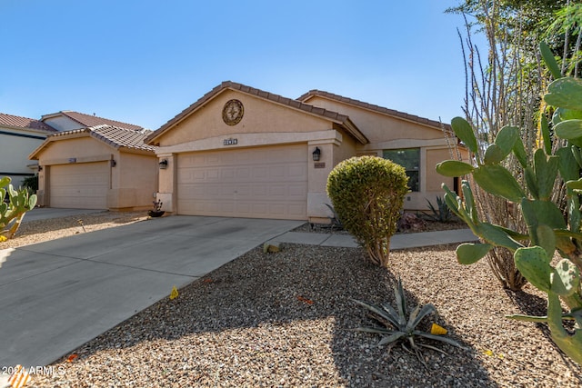 view of front of house with an attached garage, driveway, a tile roof, and stucco siding