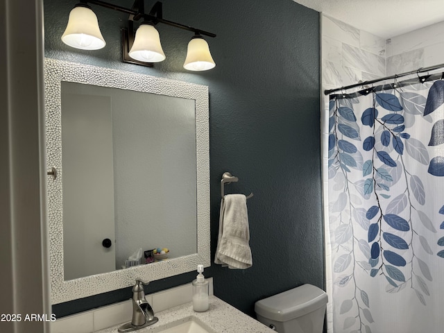 bathroom featuring a shower with shower curtain, a textured wall, vanity, and toilet