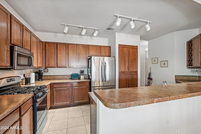 kitchen featuring light tile patterned floors, stainless steel appliances, a peninsula, visible vents, and brown cabinetry