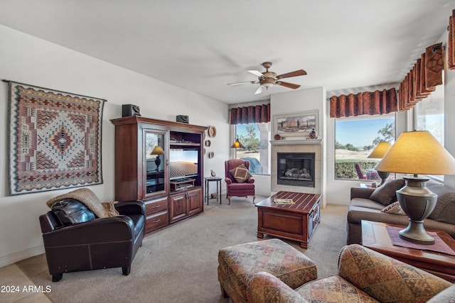 living room with ceiling fan, carpet floors, a tile fireplace, and baseboards