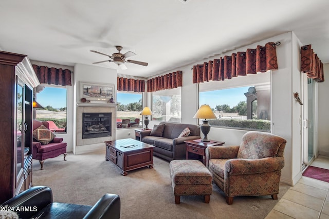 living area with light tile patterned floors, a tiled fireplace, and a ceiling fan