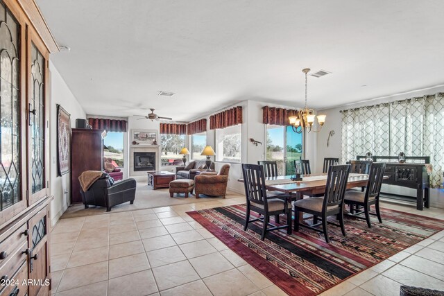 dining space featuring a healthy amount of sunlight, ceiling fan with notable chandelier, visible vents, and light tile patterned flooring