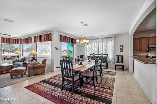 dining space featuring light tile patterned floors, visible vents, and ceiling fan with notable chandelier