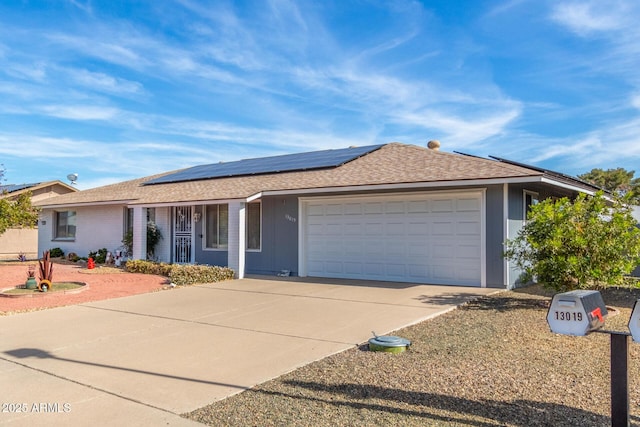 ranch-style house featuring a garage and solar panels