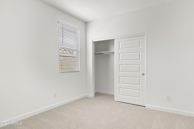 unfurnished bedroom with a closet and light colored carpet