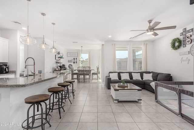 living room featuring ceiling fan, light tile patterned flooring, and sink